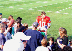 A Patriots player signs autographs for fans following practice.